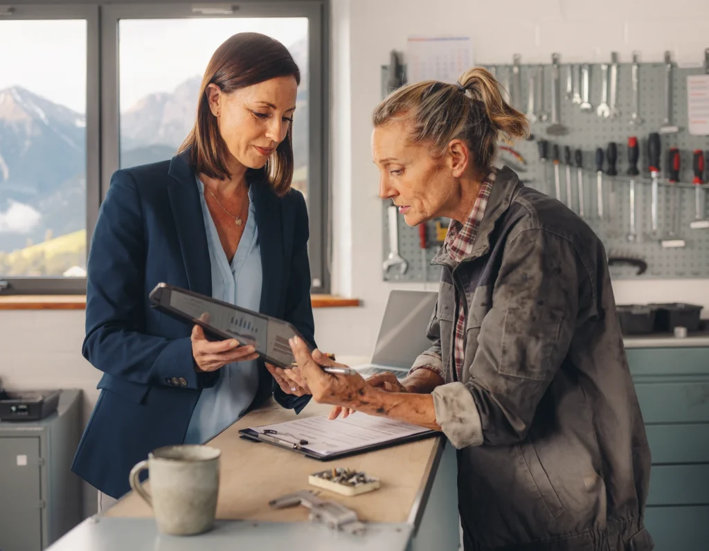 Zwei Personen besprechen einen Serviceablauf an einer Werkbank.